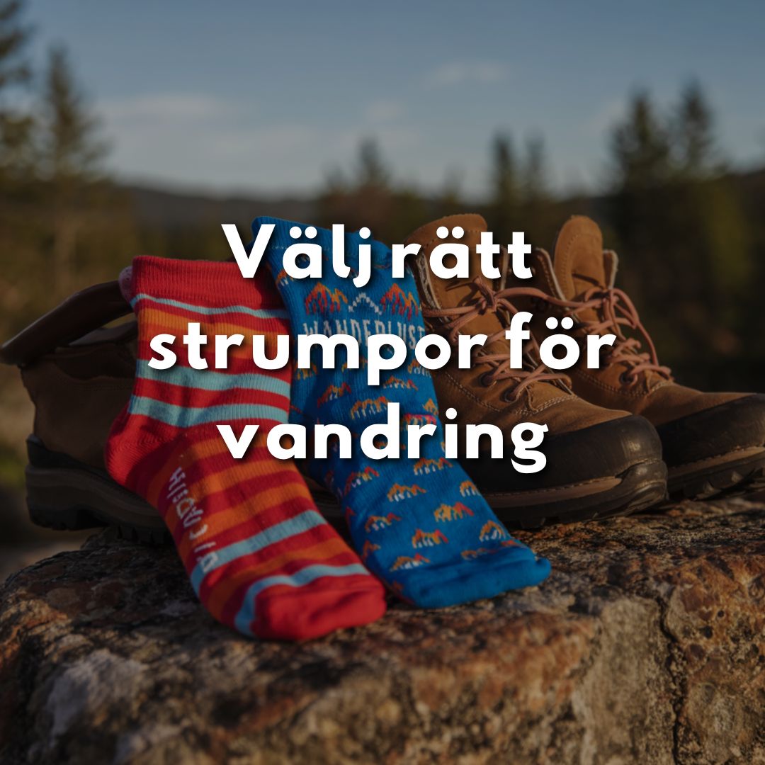Två färgglada vandringsstrumpor ligger på ett par bruna vandringskängor på en sten i naturen.