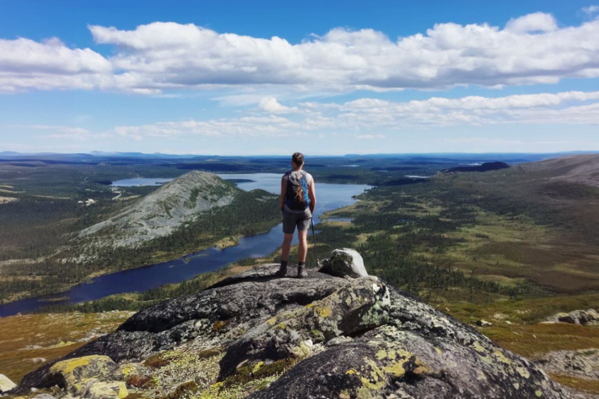 Vandring Grövelsjön guide Vildmarknaden.se Person med ryggsäck blickar ut över fjällandskap och sjöar från en klippa ovanför Grövelsjön.